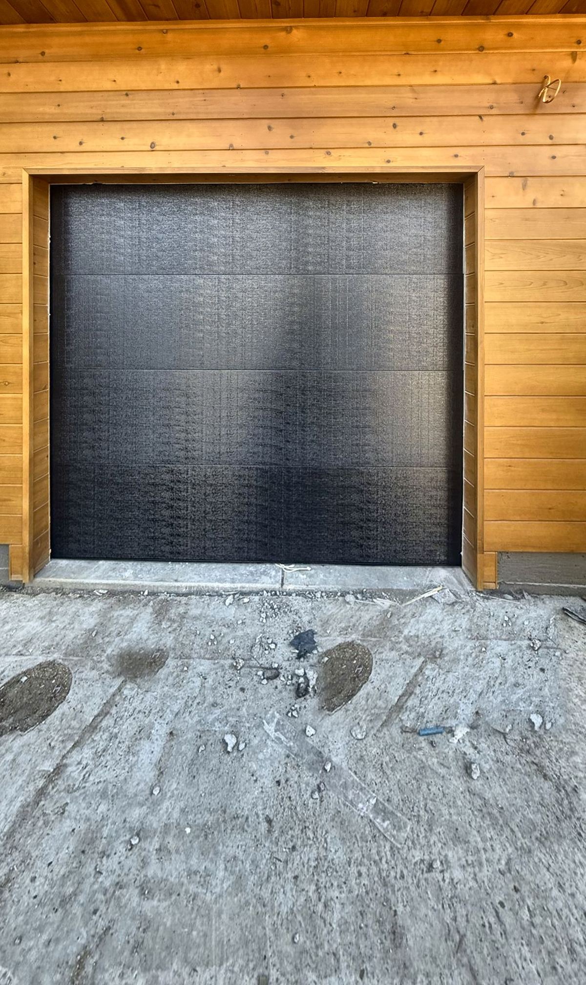 Black flush single garage door with cedar trim