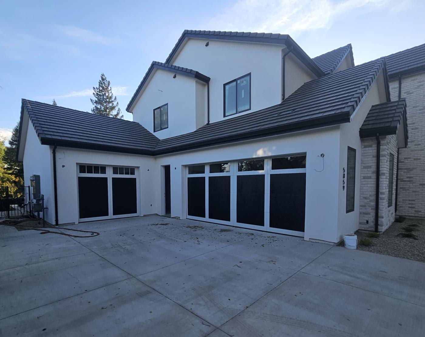 Black 4-layer garage doors with grid windows on a new home
