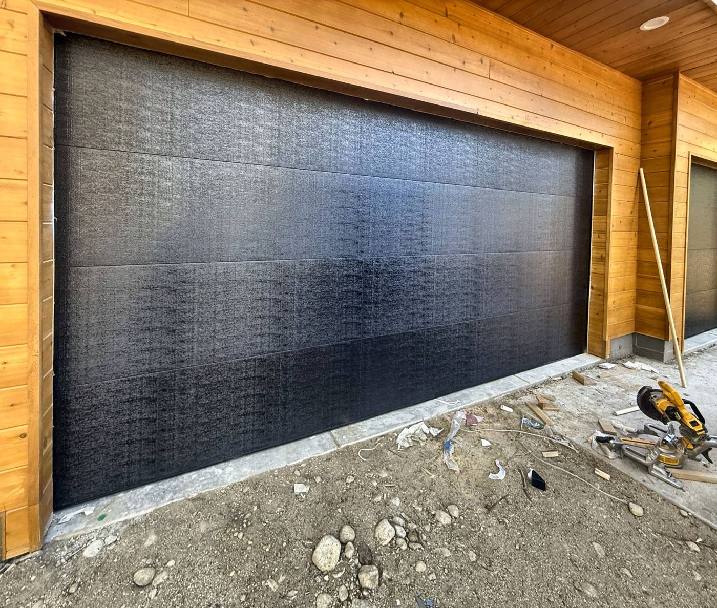 Black flush garage door with cedar trim