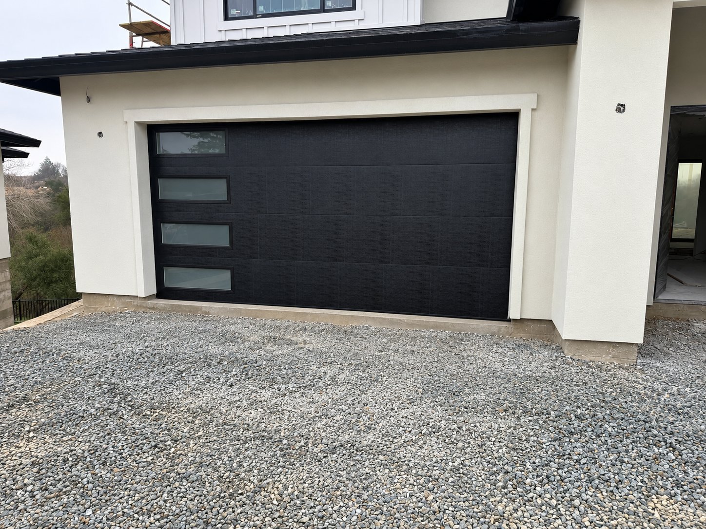 Black flush garage door with side windows on a new build