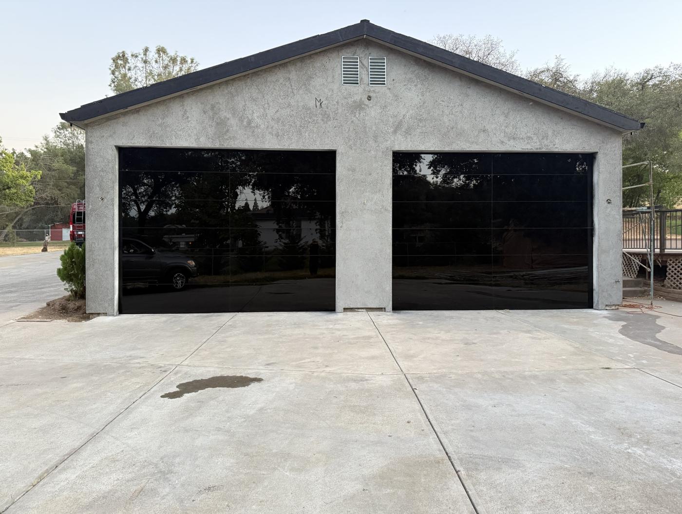 Two black glass garage doors on a stucco garage