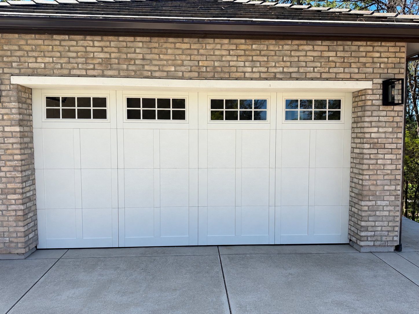White carriage-style door with grid windows on a brick home