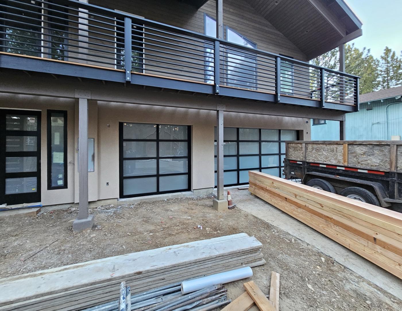 Two full-view glass garage doors under a balcony