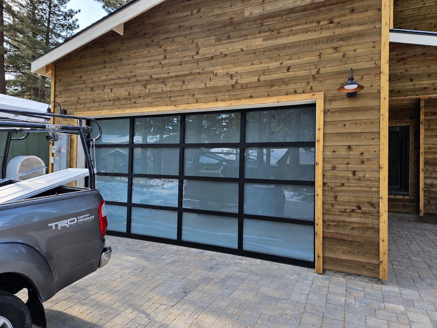 Full-view glass garage door on a cedar-sided garage