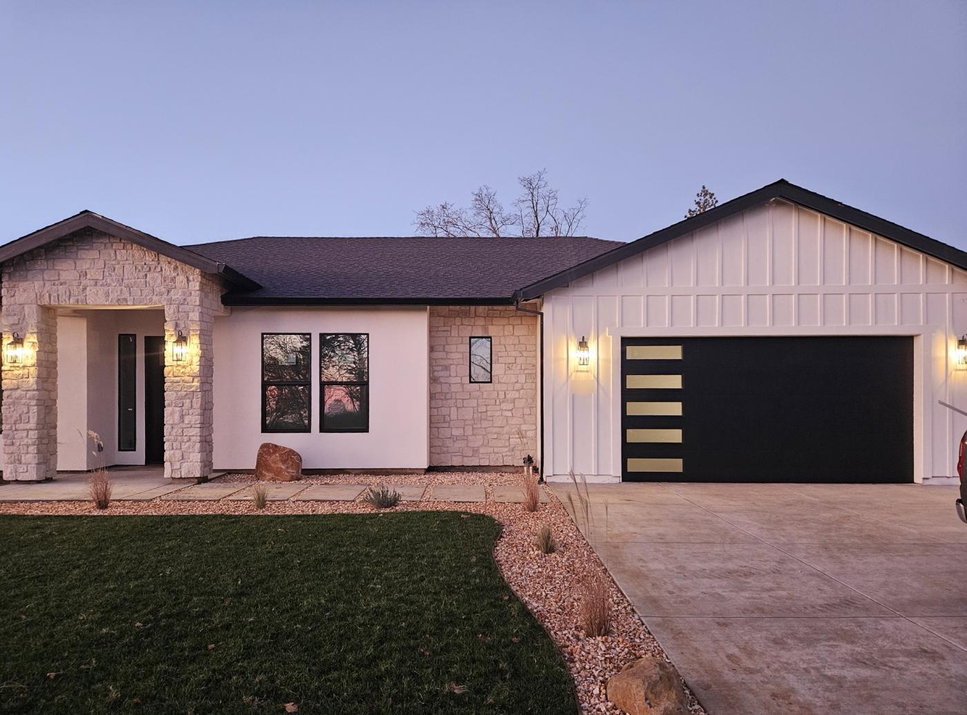 Black flush garage door with lit side windows at dusk