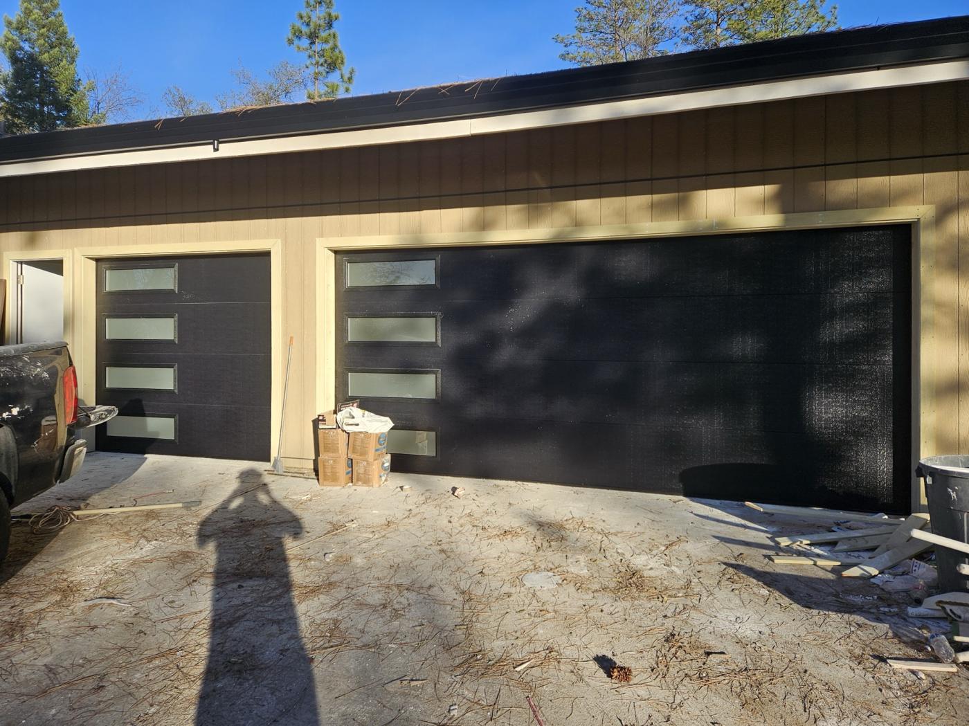 Two black flush garage doors with frosted side windows