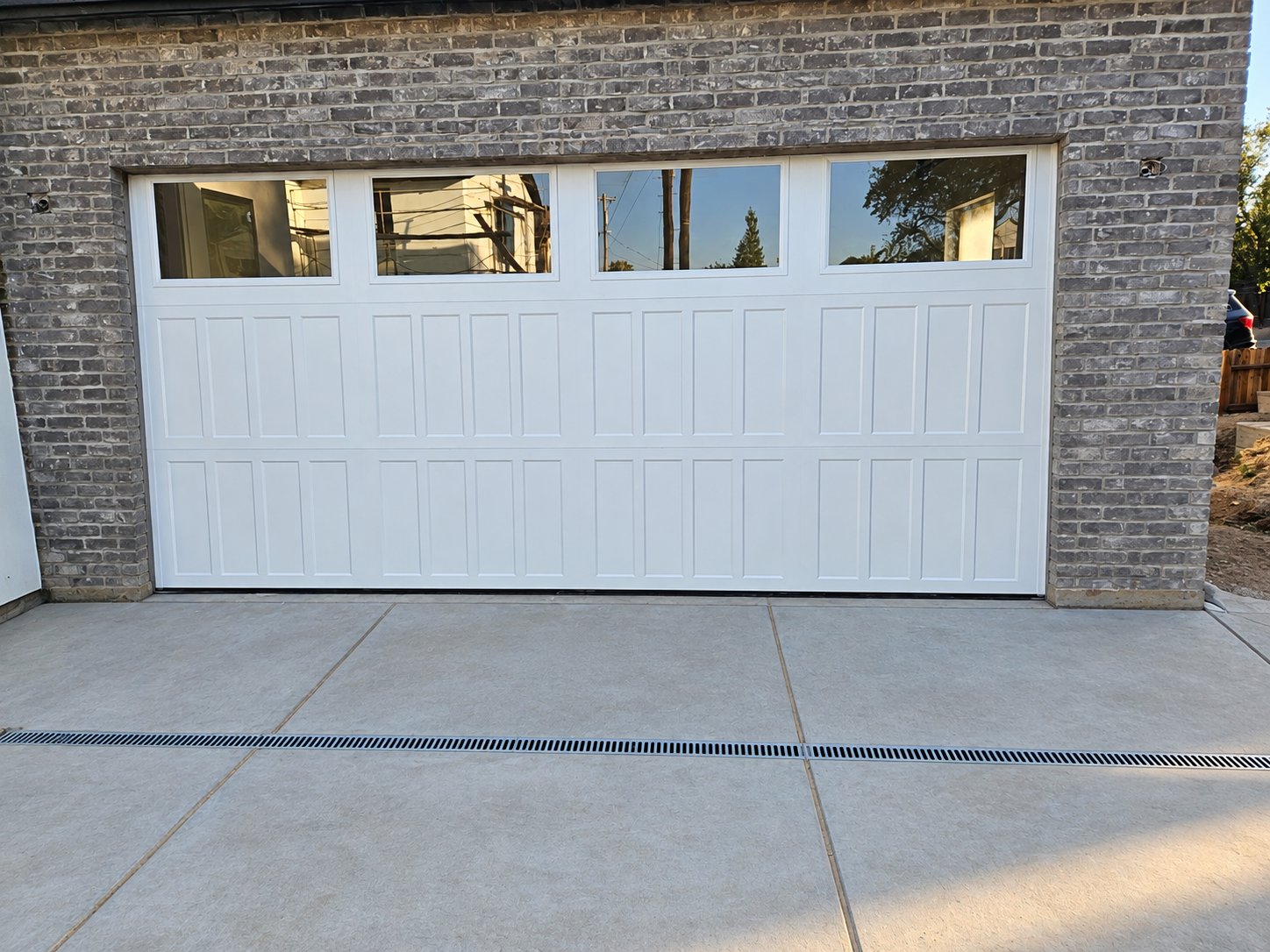 White 3-panel garage door with top windows on a brick garage