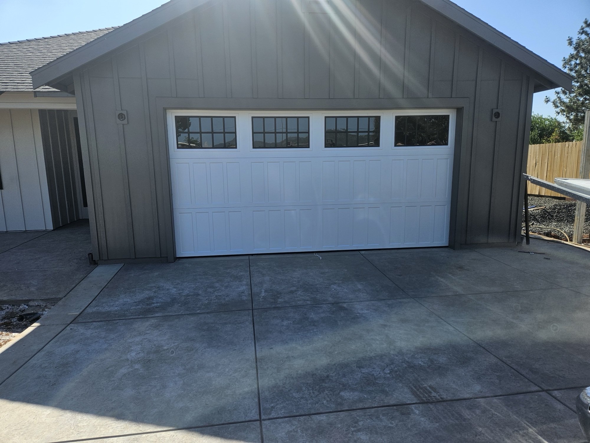White 3-panel garage door with grid windows on a gray garage