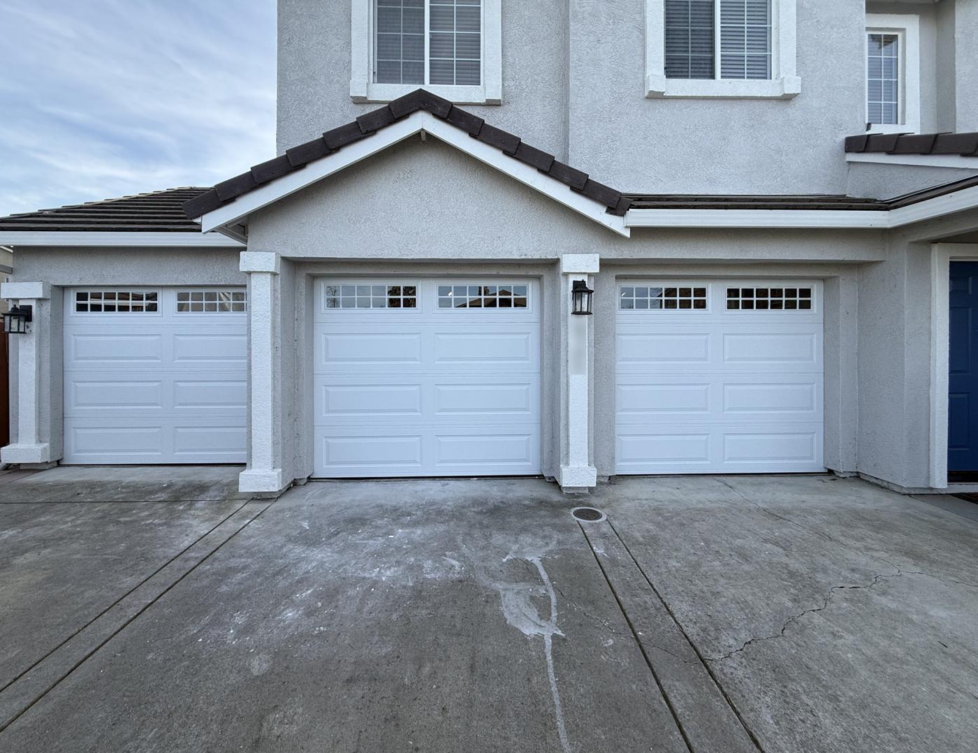 Three white raised-panel single garage doors with grid windows