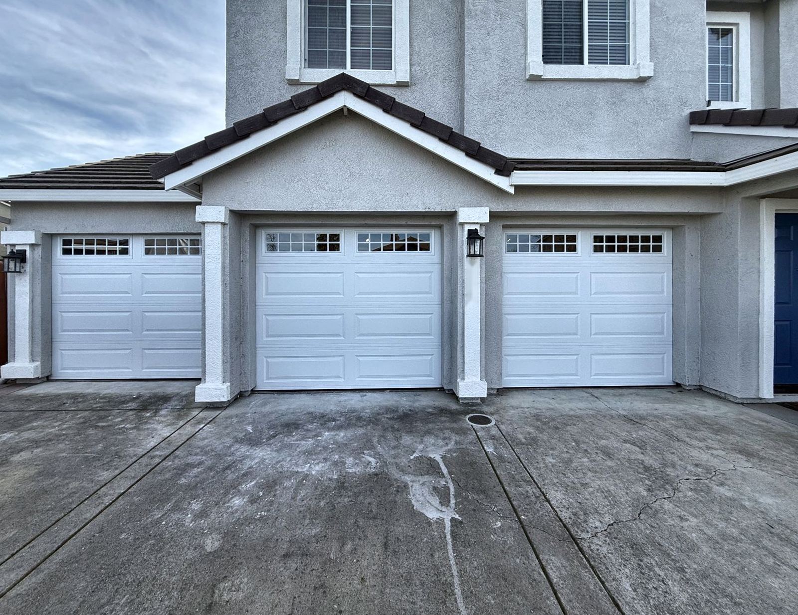 Three well-kept white garage doors with windows